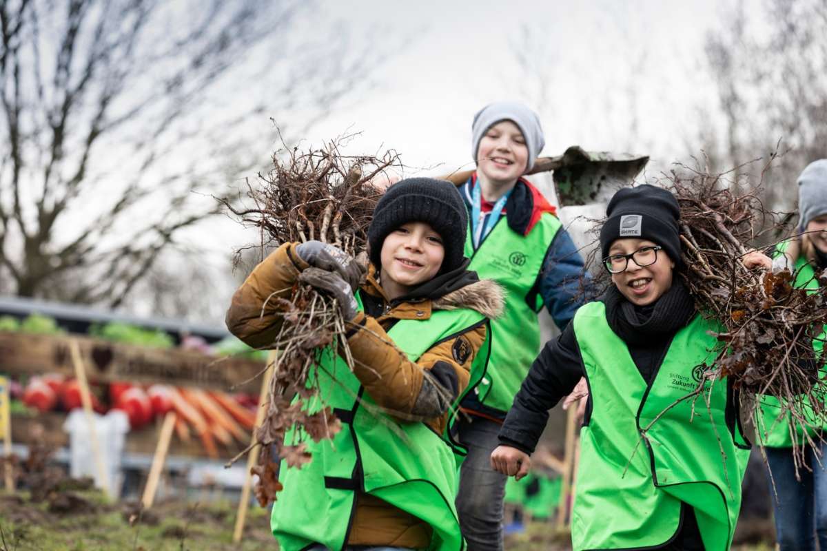 Schüler*innen bei einer Pflanzaktion tragen Setzlinge zum Pflanzkreis, (c) Stiftung Zukunft Wald