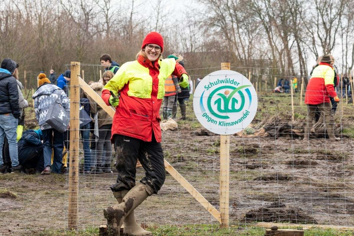 Pflanzaktion im Schulwald mit Stiftungsteam und Schild ‚Schulwälder gegen Klimawandel, (c) Stiftung Zukunft Wald